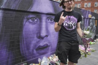 Matthew Caldwell, fan de musique, tient des fleurs en hommage à Ozzy Osbourne, décédé à Birmingham mardi. KEYSTONE/AP/Kin Cheung